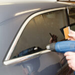 Applying tinting foil on a car window in a garage